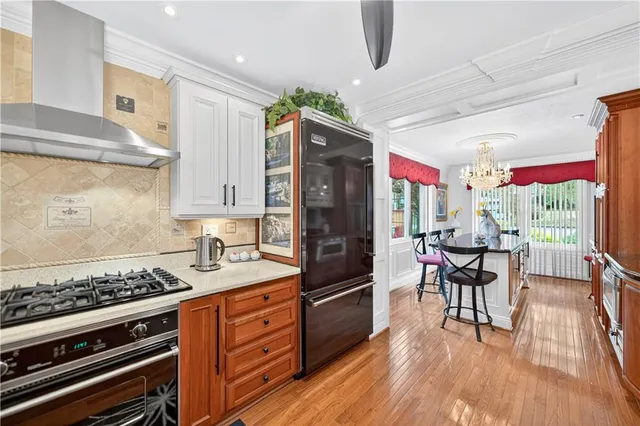 a kitchen with stainless steel appliances granite countertop a refrigerator a stove and white cabinets with wooden floor