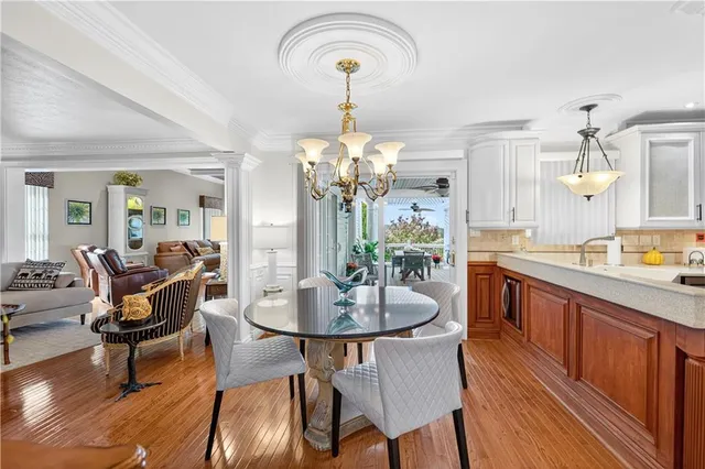 a dining room with wooden floor a chandelier a wooden table and chairs