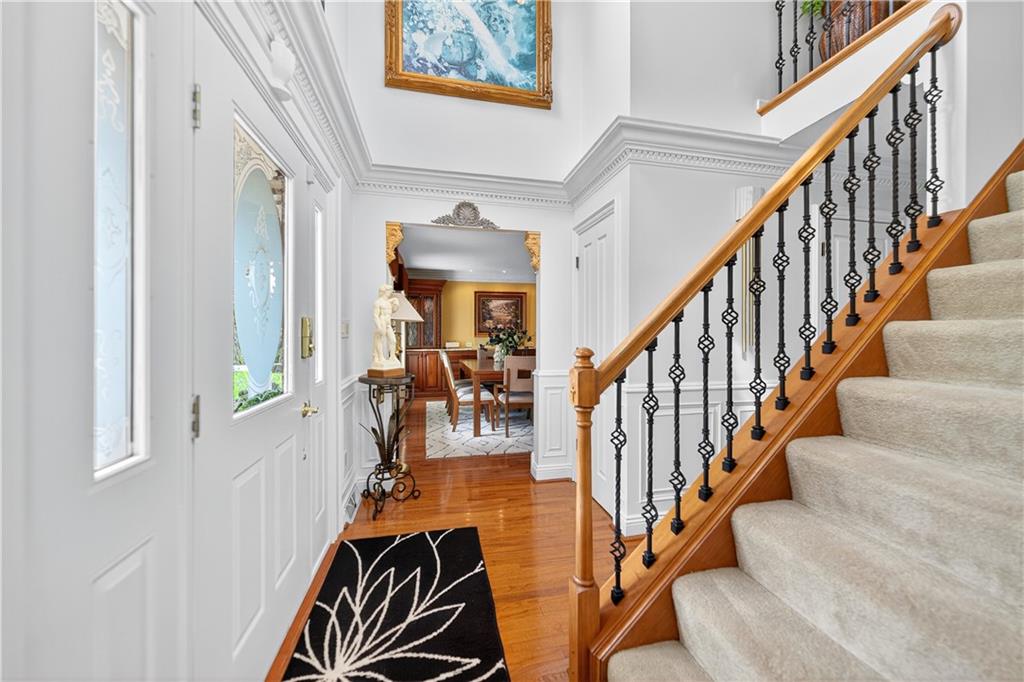 Beautiful stairway in the entry of the home with a grand ceiling and crown molding.