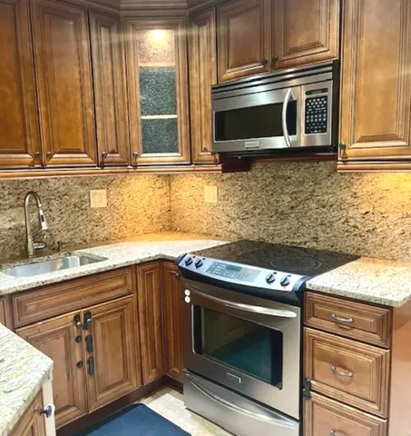 a kitchen with granite countertop stainless steel appliances a stove a microwave and sink