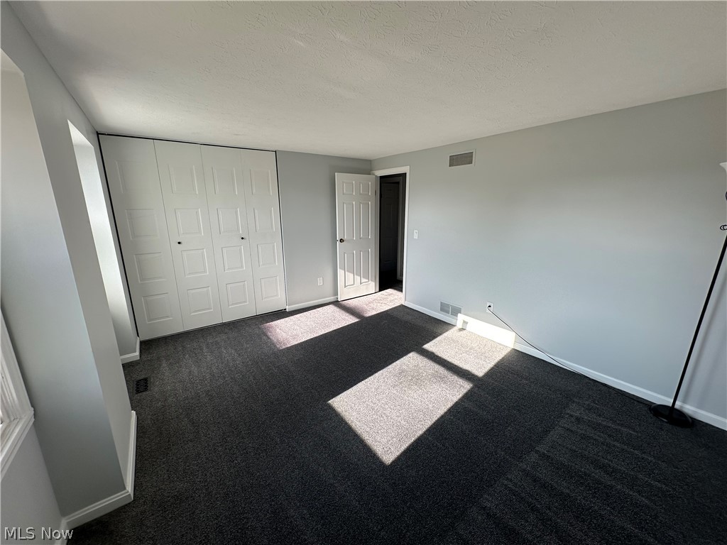 16213 Drake Road Strongsville, OH 44136 - Photo 17 of 28 Unfurnished bedroom featuring a closet, a textured ceiling, and dark carpet
