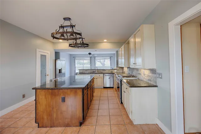 a kitchen with stainless steel appliances granite countertop a sink dishwasher stove and refrigerator with wooden floor
