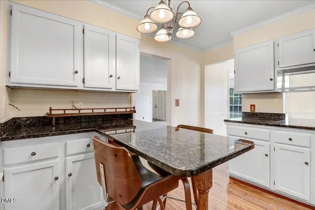 a kitchen with granite countertop stainless steel appliances a sink cabinets and wooden floor