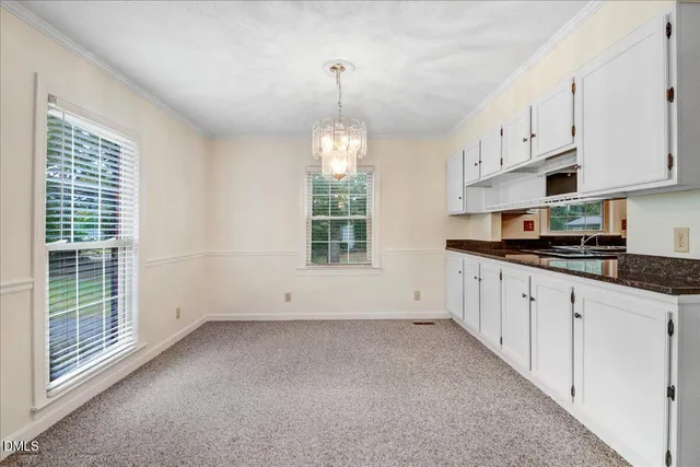 a view of kitchen with granite countertop white cabinets and window