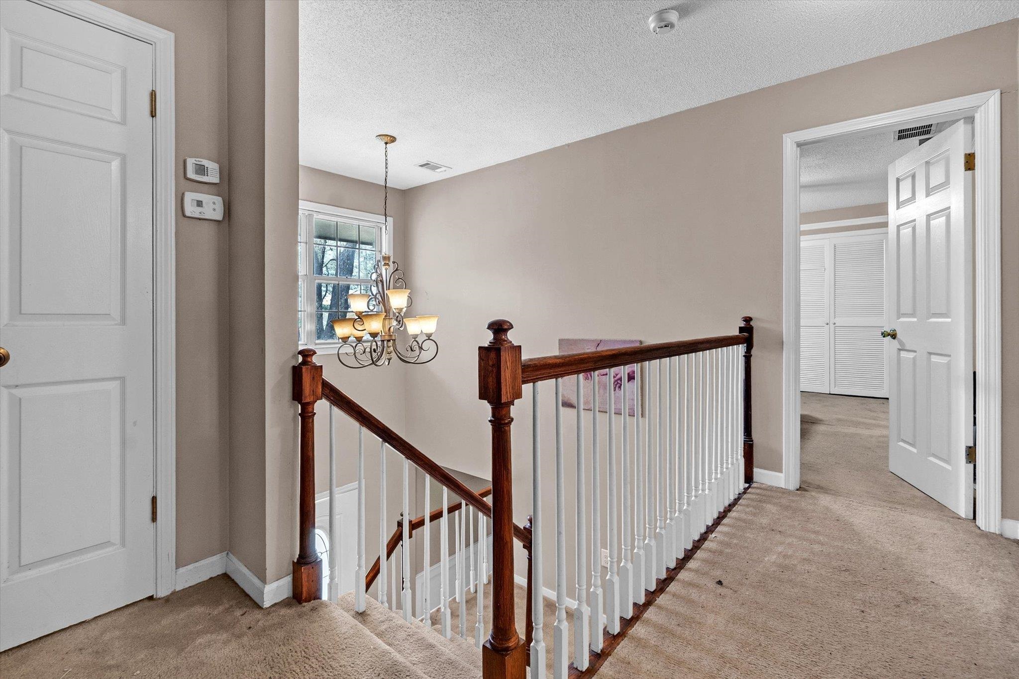 480 Friars Point Lane Memphis, TN 38018 - Photo 21 of 26 Hall with light colored carpet, an upstairs landing, a chandelier, and a textured ceiling
