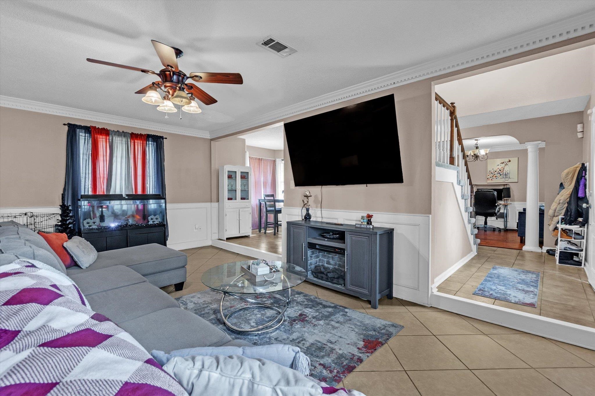 480 Friars Point Lane Memphis, TN 38018 - Photo 5 of 26 Living room featuring a wainscoted wall, light tile patterned flooring, crown molding, ceiling fan, and a decorative wall