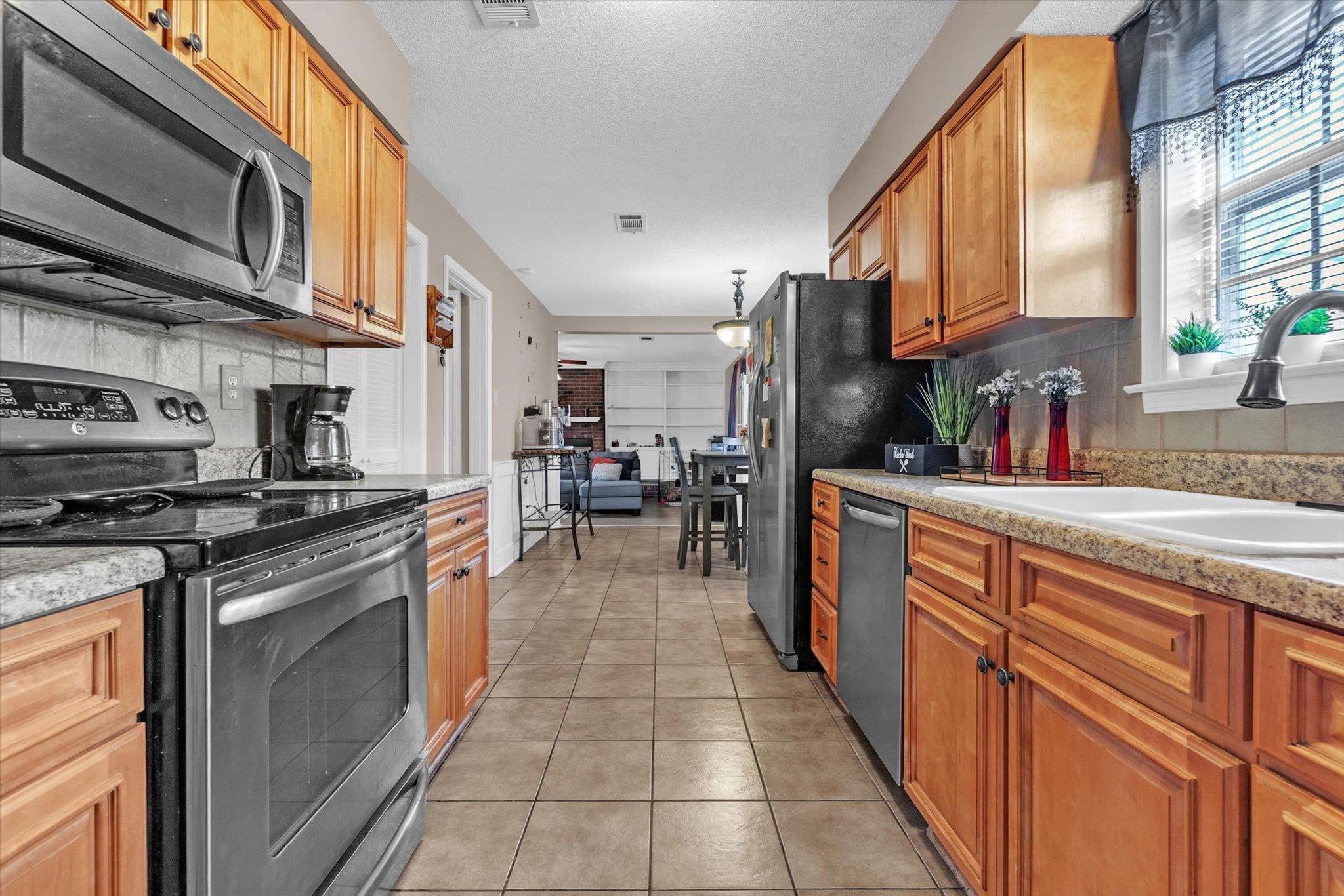 480 Friars Point Lane Memphis, TN 38018 - Photo 10 of 26 Kitchen with stainless steel appliances, light tile patterned flooring, light stone countertops, and wood finish cabinets