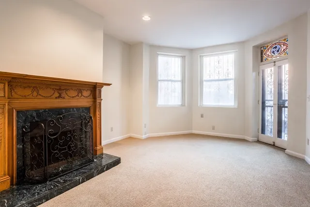 an empty room with windows and fireplace