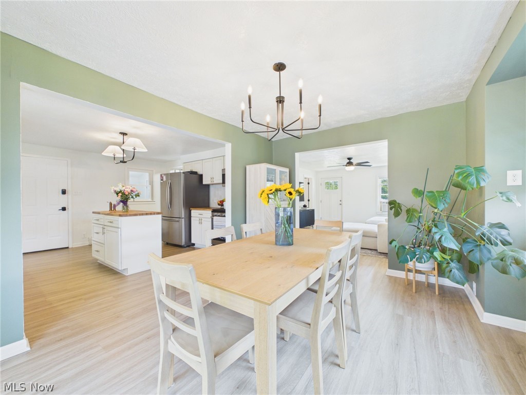 3490 County Line Road Madison, OH 44057 - Photo 7 of 42 Open-concept dining area featuring light wood-finish flooring, a contemporary chandelier, and a spacious framed opening to the kitchen