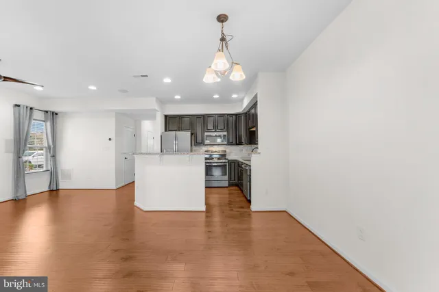 a view of a kitchen with kitchen island wooden floor and stainless steel appliances