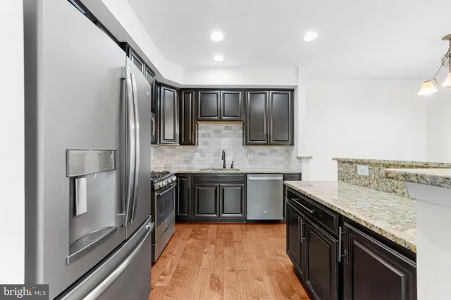 a large kitchen with stainless steel appliances granite countertop a stove and a sink