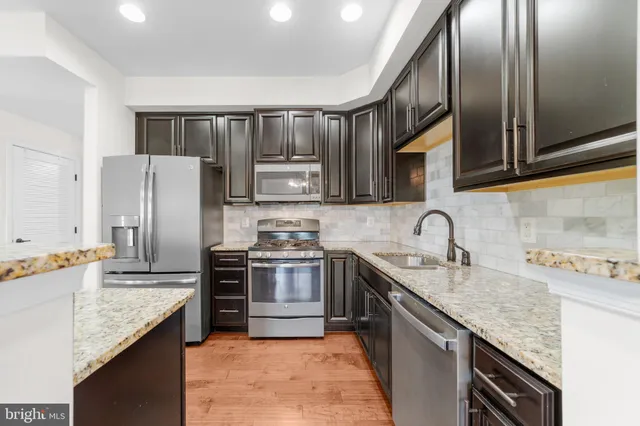 a kitchen with stainless steel appliances granite countertop a sink stove refrigerator and cabinets