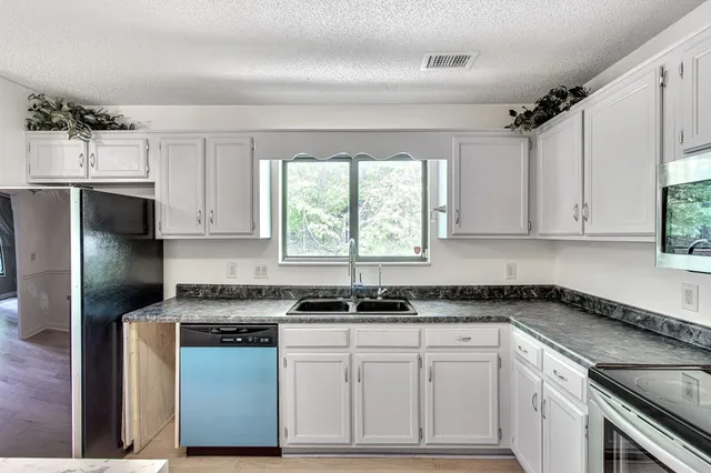 a kitchen with granite countertop a sink stainless steel appliances a window and cabinets