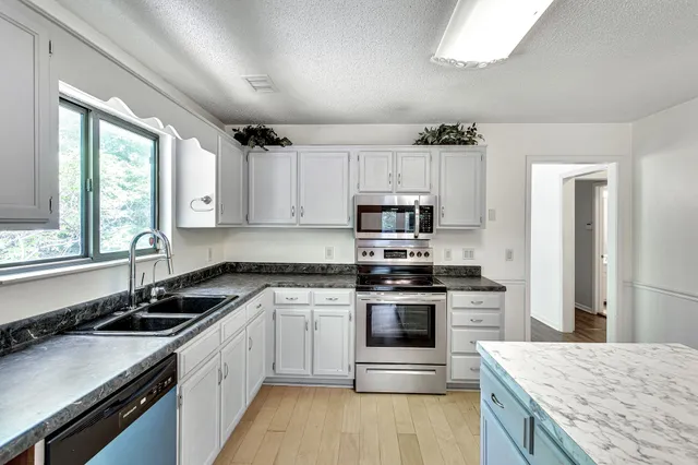 a kitchen with stainless steel appliances granite countertop a sink stove and refrigerator