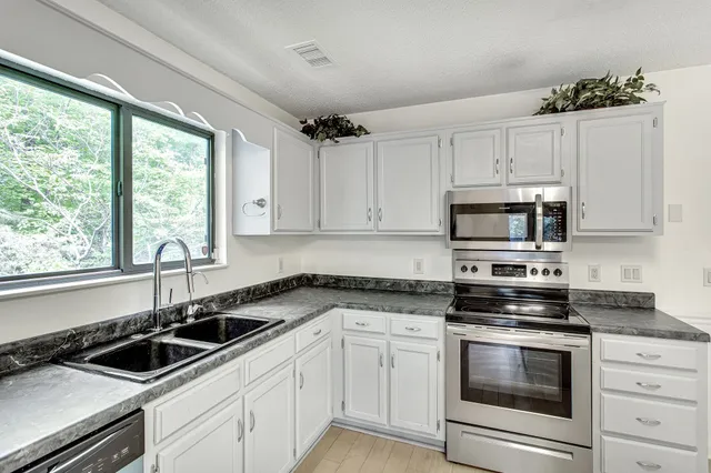 a kitchen with granite countertop white cabinets and white appliances