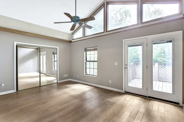 a view of an empty room with a window and wooden floor