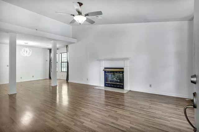 an empty room with wooden floor fireplace and windows