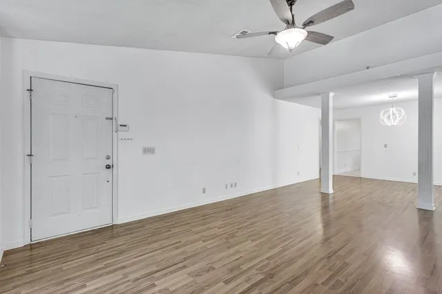 an empty room with wooden floor and fan