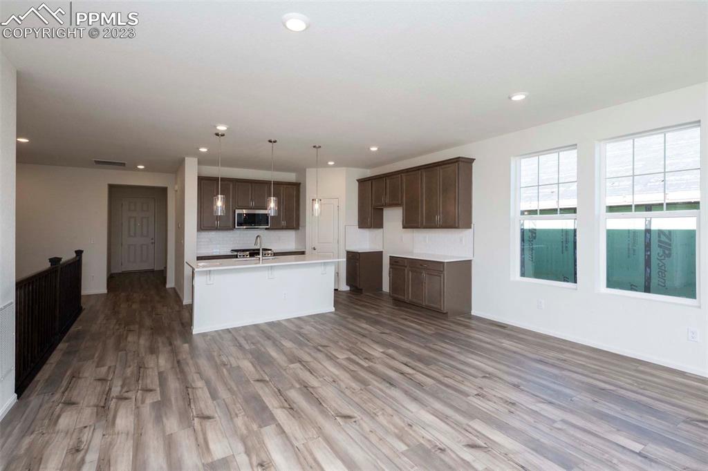 2057 Peachleaf Loop Castle Rock, CO 80108 - Photo 6 of 23 a large kitchen with kitchen island a sink dishwasher stove and white cabinets with wooden floor