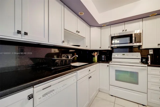a kitchen with granite countertop white cabinets and black appliances