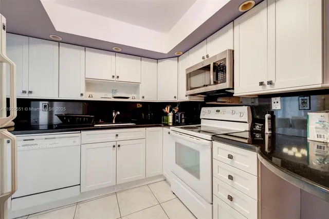 a kitchen with stainless steel appliances granite countertop white cabinets sink and a stove