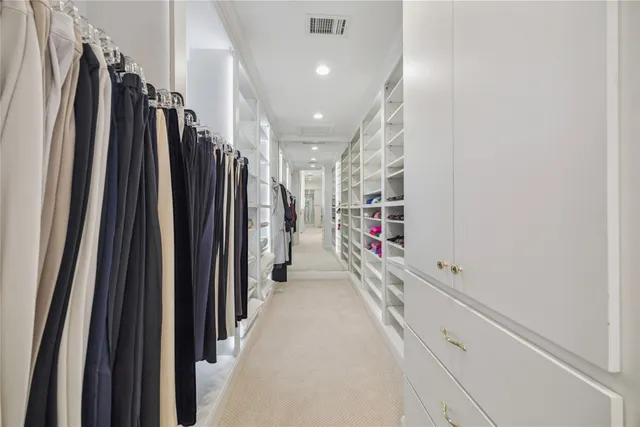 a view of walk in closet with clothes and shoes