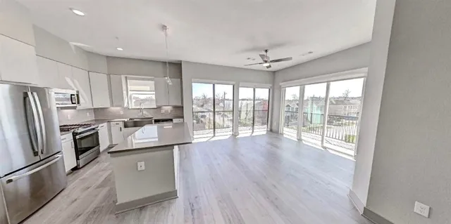 a kitchen with stainless steel appliances a refrigerator a sink dishwasher a stove and white cabinets with wooden floor