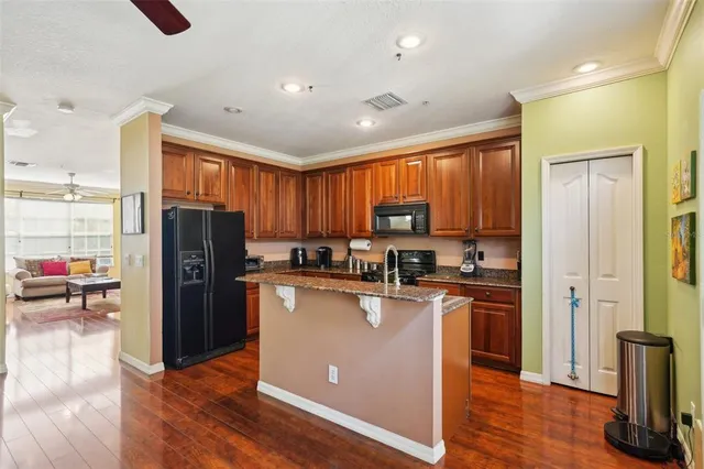 a kitchen with kitchen island granite countertop a refrigerator a sink a stove top oven and cabinets