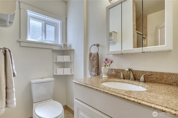 a bathroom with a granite countertop toilet sink and mirror