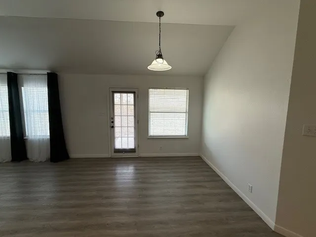 an empty room with wooden floor and window