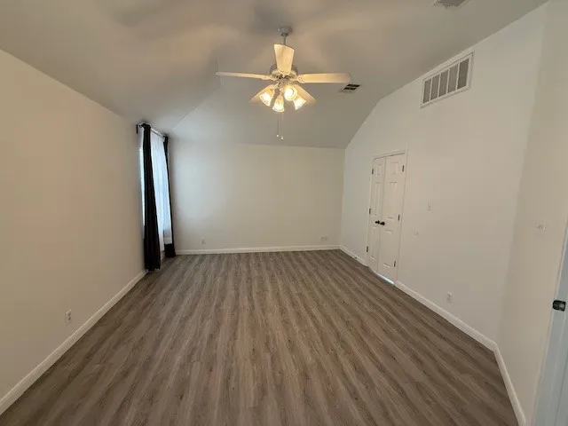 a view of empty room with wooden floor and fan