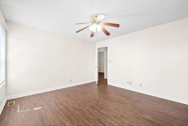 an empty room with wooden floor chandelier fan and closet area