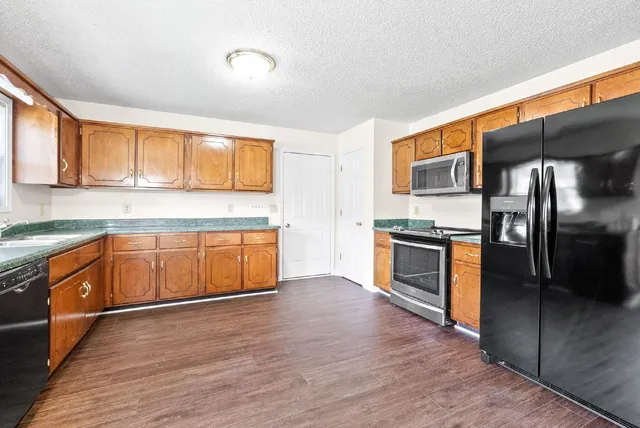 a kitchen with stainless steel appliances kitchen island granite countertop a stove a sink and a refrigerator