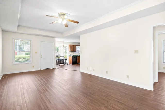 an empty room with wooden floor chandelier and windows