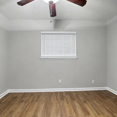an empty room with wooden floor and window