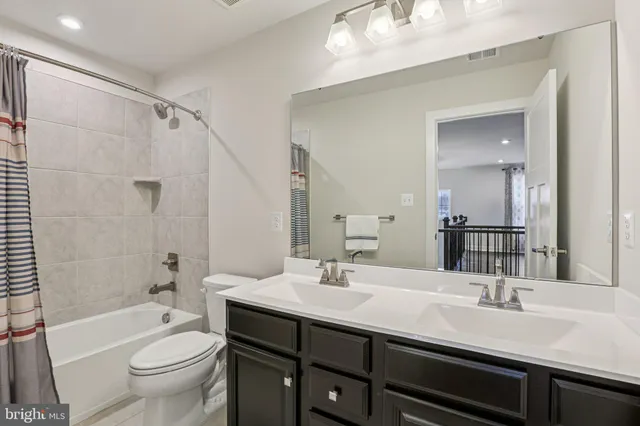 a bathroom with a double vanity sink toilet mirror and shower
