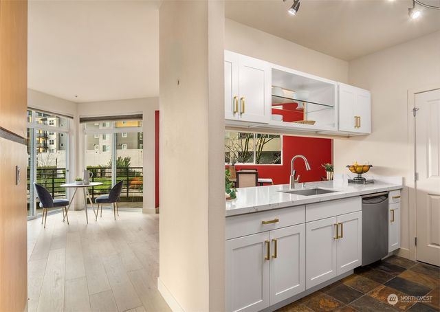 a kitchen with white cabinets and dining table with wooden floor