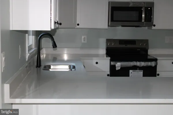 a kitchen with stainless steel appliances a refrigerator a stove and white cabinets