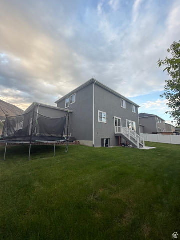 437 North 650 E Street Springville, UT 84663 - Photo 3 of 11 Expansive green lawn surrounds the rear of the property, featuring a two-story residence with gray siding and white trim