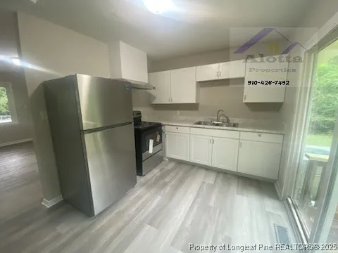 a kitchen with stainless steel appliances a refrigerator sink and wooden floor