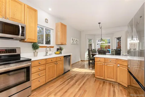 a large kitchen with stainless steel appliances granite countertop a stove and a wooden floors
