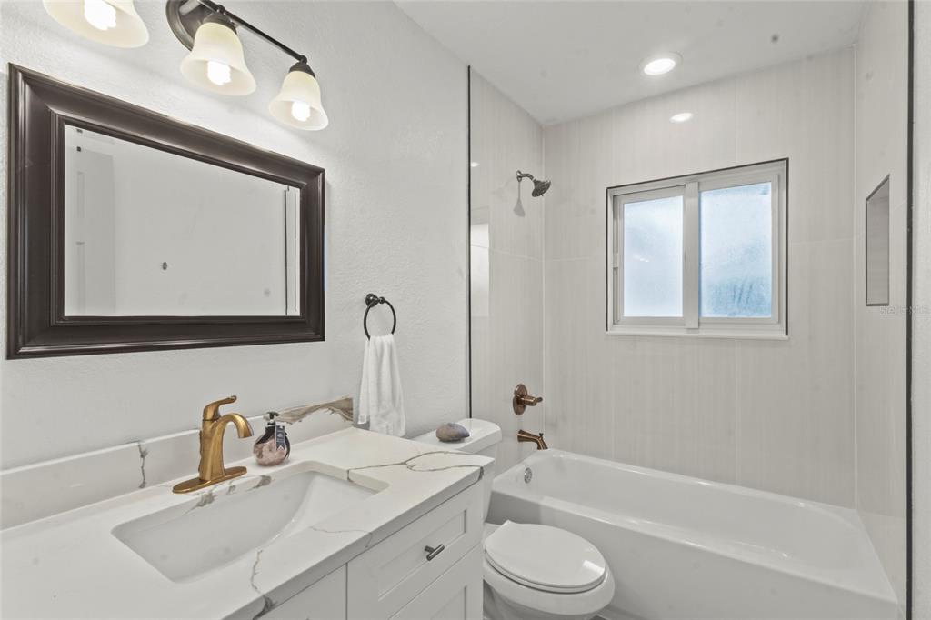 7230 Shepherd Street Sarasota, FL 34243 - Photo 23 of 30 a bathroom with a toilet a sink a mirror a bathtub and vanity