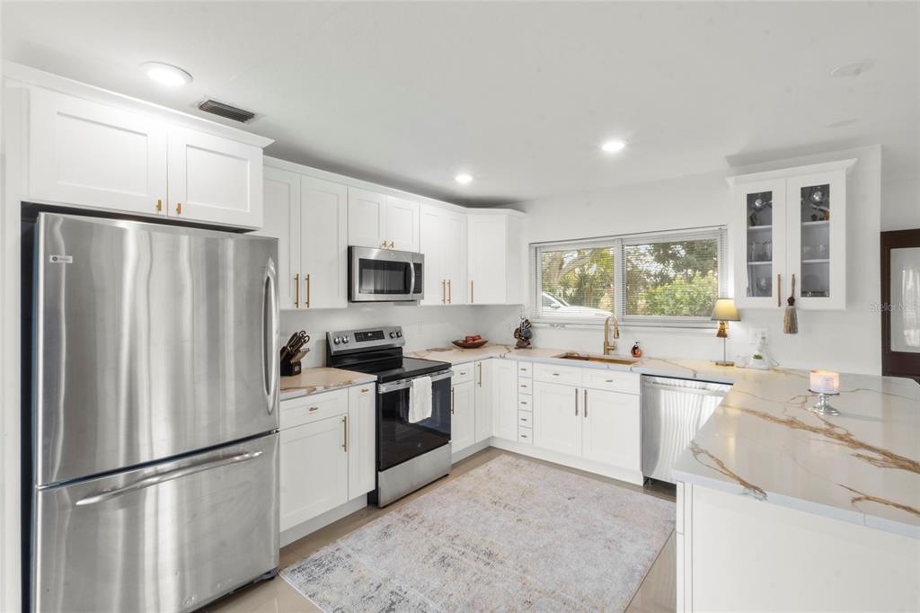 7230 Shepherd Street Sarasota, FL 34243 - Photo 10 of 30 a kitchen with white cabinets and stainless steel appliances