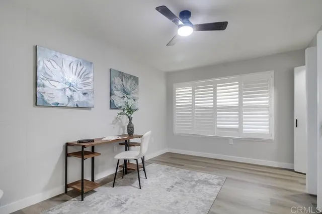 a view of empty room with wooden floor and fan