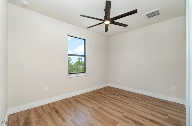 an empty room with a window and a ceiling fan
