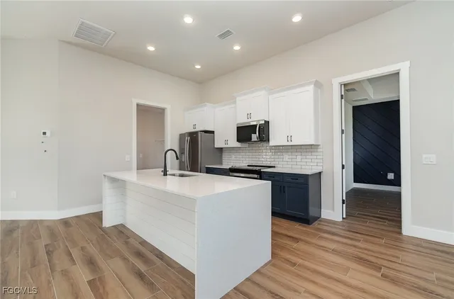 a large kitchen with stainless steel appliances a sink and cabinets