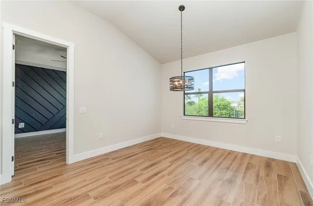 a view of empty room with wooden floor and window