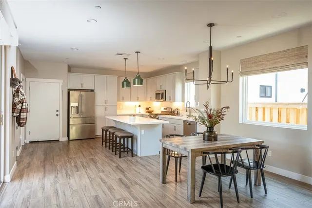 a kitchen with stainless steel appliances a dining table chairs and wooden floor