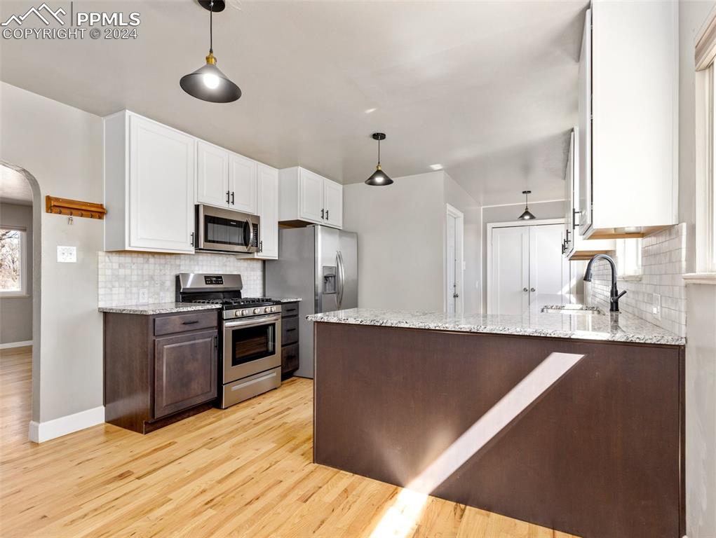 65 University Circle Pueblo, CO 81005 - Photo 4 of 32 a kitchen with stainless steel appliances granite countertop a sink a stove top oven a refrigerator with white cabinets and wooden floor