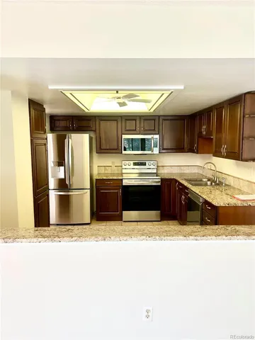 a kitchen with stainless steel appliances granite countertop a sink and a refrigerator